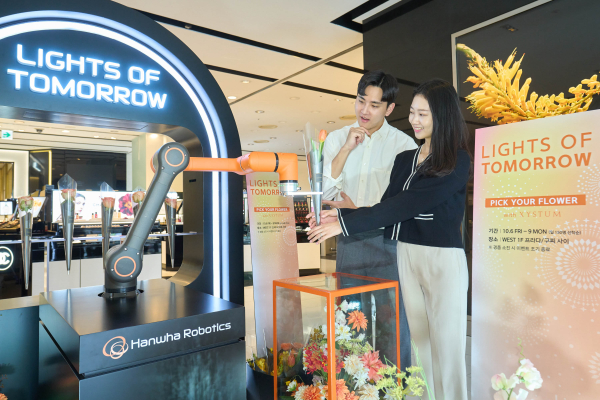갤러리아백화점 서울 명품관에서 한 고객이 로봇이 건네주는 꽃을 받고 있다.